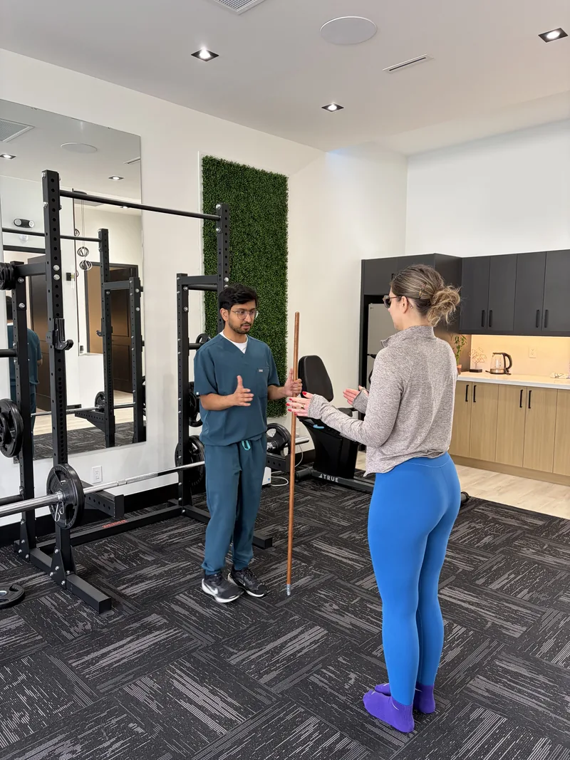 Dhiman Patel coaching a patient through a movement exercise in the rehab gym at Interlink Physiotherapy Ancaster