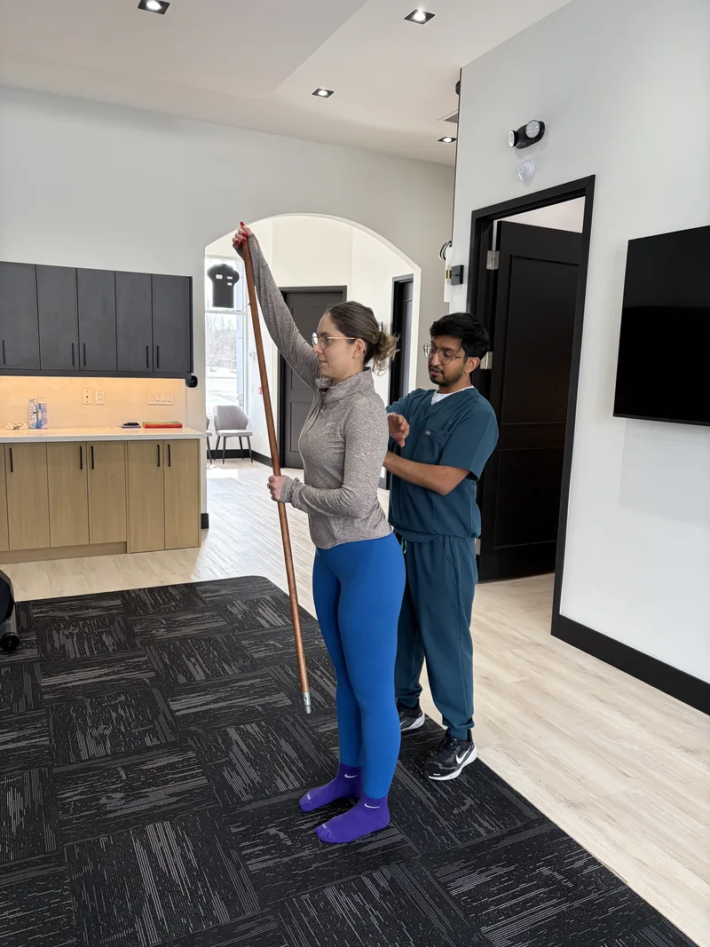 Dhiman Patel guiding a patient through a shoulder mobility exercise